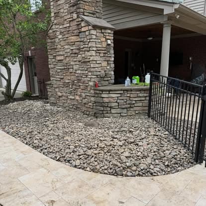 Landscaped patio with stone chimney, gravel ground, and fenced area for outdoor living space.