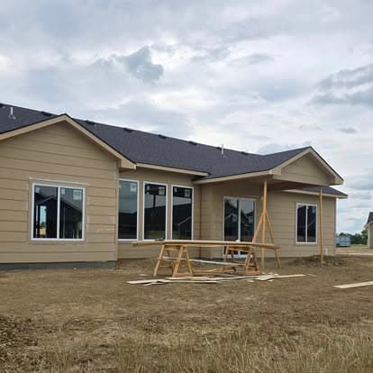 Newly constructed single-family home with wooden scaffolding and cloudy sky backdrop.