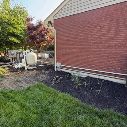 Brick home exterior with landscaped garden, plumbing features, and green grass.