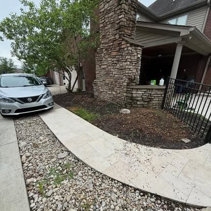 Nissan sedan parked beside a stone pathway and green landscaping outside a modern home.