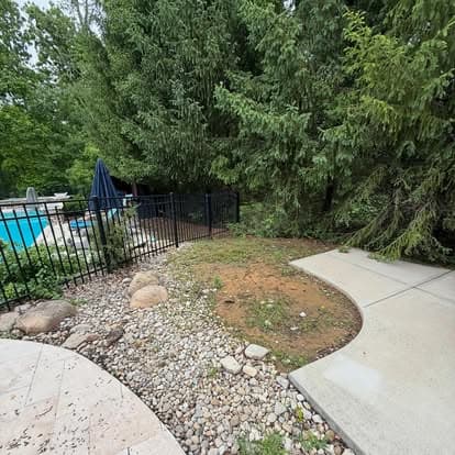 Lush green vegetation surrounds a pool area with a paved path and rocky landscaping.